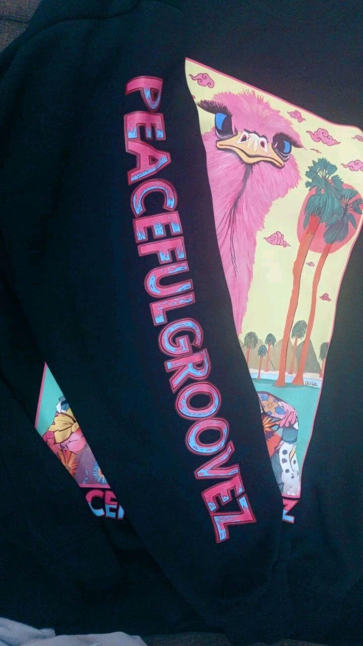Ostrich Groove Sweatshirt | Hand-Drawn Pink Ostrich with Blue Eyes & Long Eyelashes Wearing Navy Floral Bomber Jacket Yellow Checkered Collar & Silver Peace Sign Necklace Under Tropical Palms Red Sun & Pink Swirling Clouds with PEACEFULGROOVEZ Sleeve Print | Surreal Weird Art Unique Standout Anti Mainstream Indie Vanguard Dopamine Dressing Heavyweight Archive Streetwear 2026 by Kurt Wollton DARO Studio